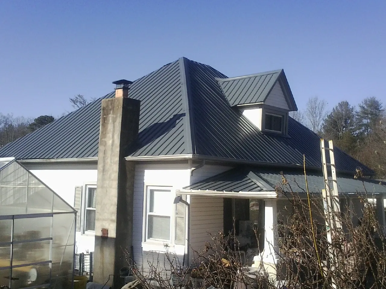 Dark blue standing seam metal roof on a white farmhouse with dormer — Slate & Tile Roof Repair by Roofing Brothers in Thompsontown
