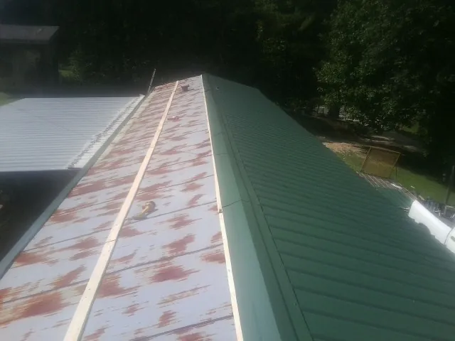 Old rusted panels beside newly installed green metal roofing — Wind Damage Roof Repair by Roofing Brothers in Thompsontown