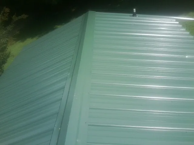 New green metal panels meeting at the ridge of a roof — Flat Roof Repair work by our crew in Thompsontown