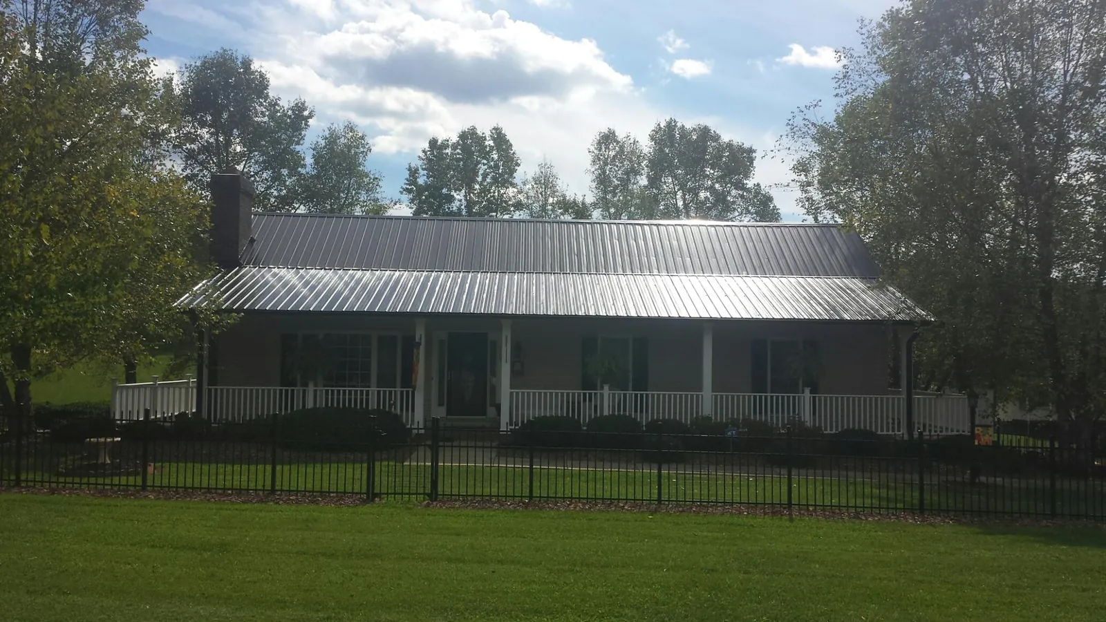 Gray metal roof on a brick ranch with a full width front porch — Gutter Guard Installation work by our crew in Thompsontown