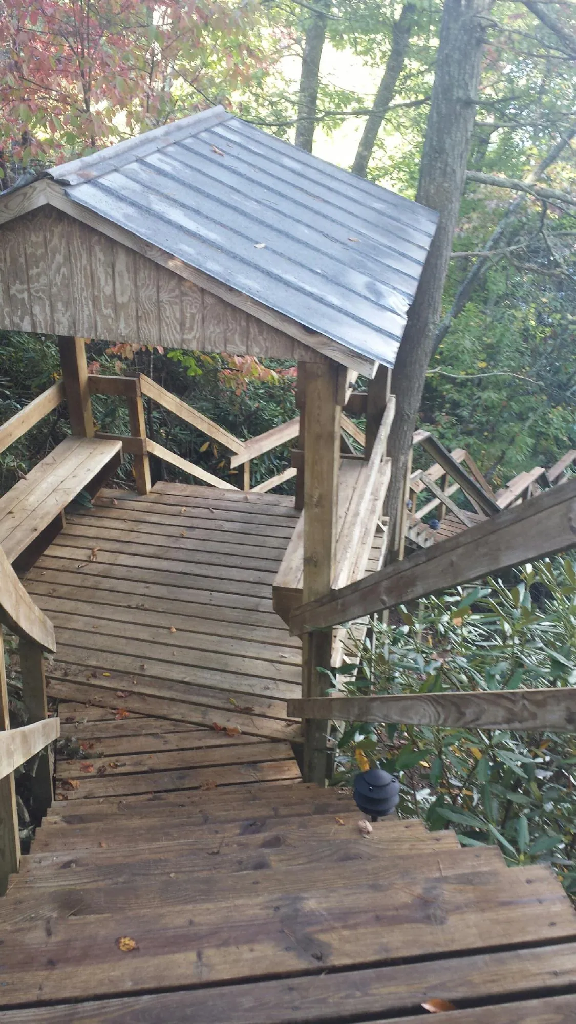 Metal roofed shelter over wooden steps on a wooded walkway — Skylight Repair & Installation work by our crew in Thompsontown