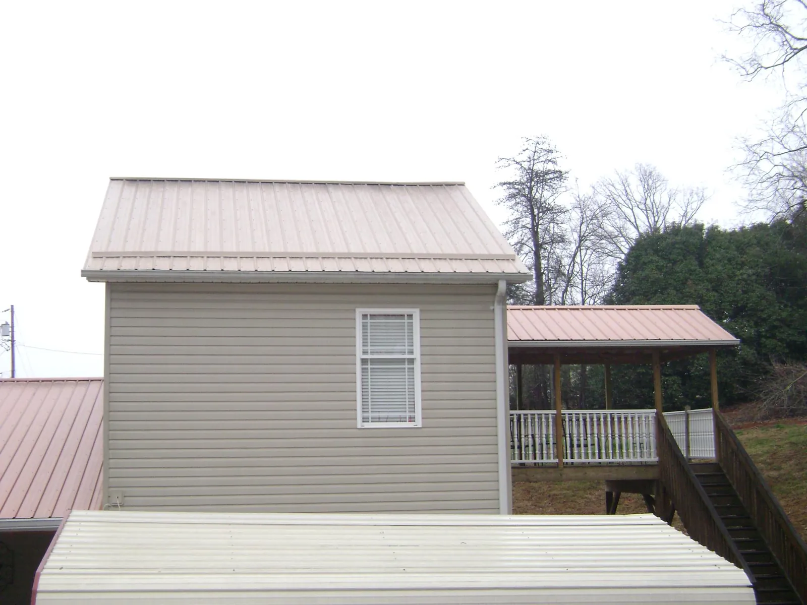 Tan metal roofs on a two story addition and attached porch, from a Roof Replacement job in Thompsontown