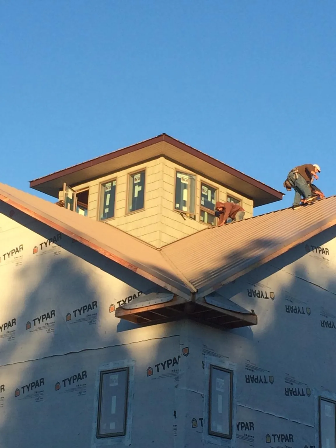 Roofers working around a rooftop cupola on a new metal roof at sunset — Roof Waterproofing in Thompsontown by Roofing Brothers